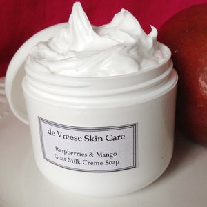 May include: White jar of de Vreese Skin Care Raspberry & Mango Goat Milk Creme Soap.