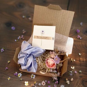 Coffret cadeau fantaisie pour demoiselle d'honneur avec épingle à cheveux à fleurs roses et violettes, chouchou en satin bleu et carte « Veux-tu être ma demoiselle d'honneur ? »