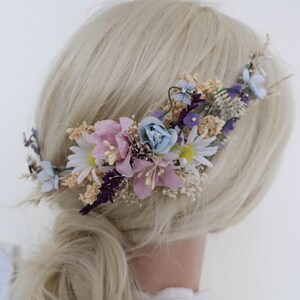 Könnte beinhalten: Ein Blumenhaar kamm mit rosa, blauen und weißen Blumen. Der Kamm ist aus Metall und hat ein zartes Design.