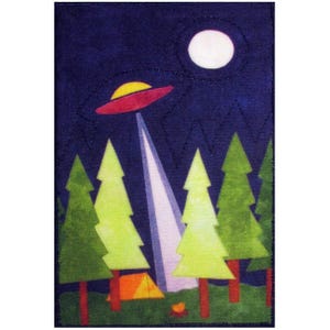 May include: A fabric patch featuring a night scene with a red and yellow UFO beaming light down on a campsite. The scene includes green trees, an orange tent, a campfire, and a full moon against a dark blue sky.