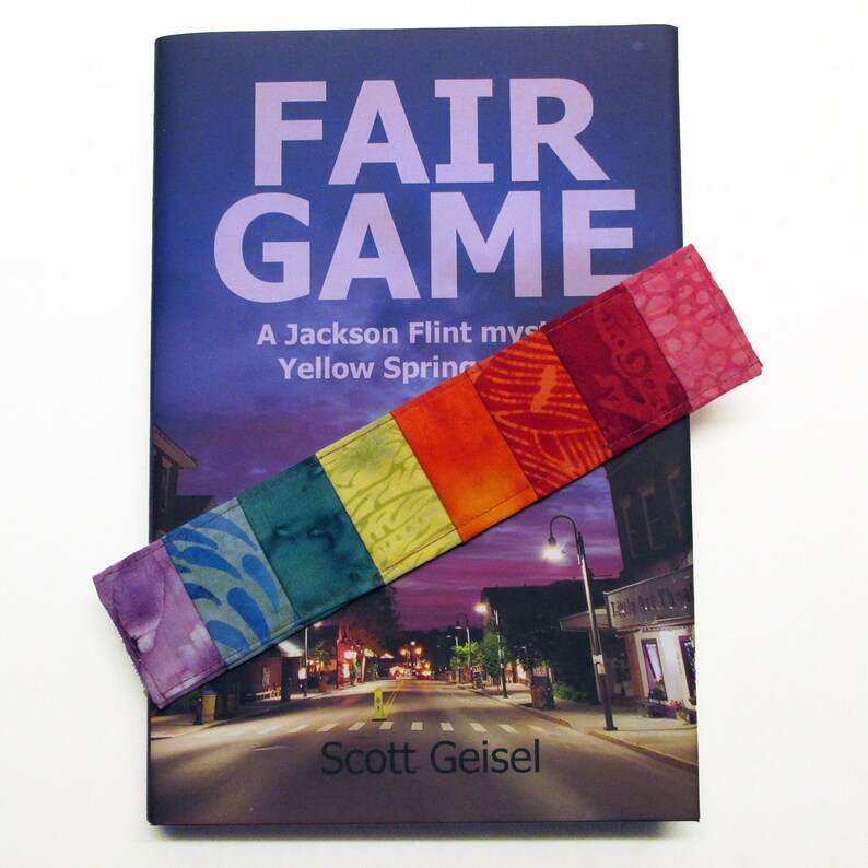 以下が含まれることがあります： スコット・ガイゼル著「フェアゲーム」というタイトルの本。イエロー・スプリングスを舞台にしたジャクソン・フリントのミステリー。カラフルな布製のしおり付き。