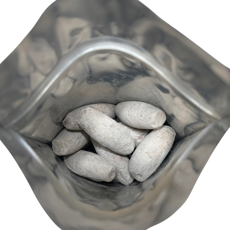 May include: A silver foil pouch filled with gray, oval-shaped candies.
