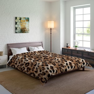 May include: A bed with a brown wooden frame and a comforter featuring a leopard print pattern in shades of brown, tan, and black. The room has white walls, a window, and a floor lamp.
