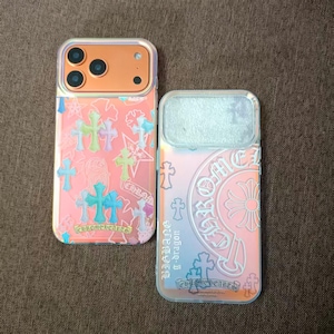 Puede incluir: Dos fundas para teléfono con un acabado rosa e iridiscente. Una funda presenta un patrón de cruces coloridas, mientras que la otra tiene un diseño circular con el texto "Chrome Hearts" y el texto "BIGBANG g-dragon".