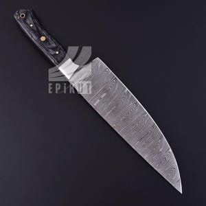 May include: A black-handled chef's knife with a Damascus steel blade. The blade has a wavy pattern and a pointed tip.