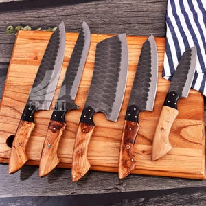 May include: Five kitchen knives with wooden handles on a wooden cutting board. The knives have black blades with a hammered finish.