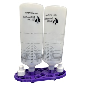 May include: Two white 1-litre mixing bottles with graduated markings and the text "Groom Professional." The bottles are on a purple base with white caps. The bottles are designed for mixing liquids.
