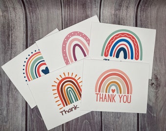 May include: Set of six blank greeting cards featuring colourful rainbow designs. Each card has a different rainbow design with a heart at the top. The cards are perfect for sending a thank you note or a special message.