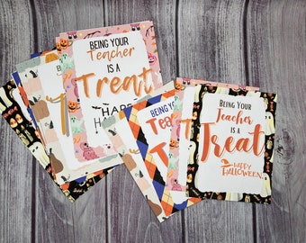 May include: A stack of colorful Halloween-themed cards with the text "Being your teacher is a treat" and "Happy Halloween".
