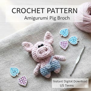 以下が含まれることがあります： ピンクとブルーの、ボタン付きかぎ針編みアミグルミ豚ブローチ。画像には、葉の形をした装飾品、かぎ針、毛糸玉も写っています。テキストは「CROCHET PATTERN Amigurumi Pig Brooch」と「Instant Digital Download US Terms」です。