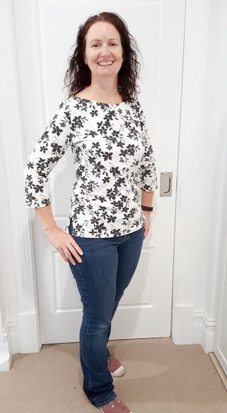May include: A woman wearing a white and black floral print top with 3/4 sleeves and blue jeans.