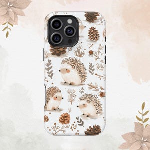 Op de afbeelding: Witte telefoonhoes met een herhalend patroon van cartoon egels, dennenappels en takjes. De egels hebben bruine en beige stekels, met kleine zwarte ogen en neuzen. De hoes heeft een glanzende afwerking.