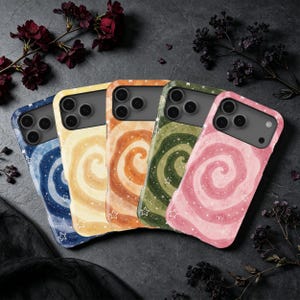 May include: Five smartphone cases arranged in a row, each featuring a spiral galaxy-inspired design with small white star outlines and a speckled finish. The cases are colored in blue, yellow, orange, green, and pink, all with a dark camera cutout.