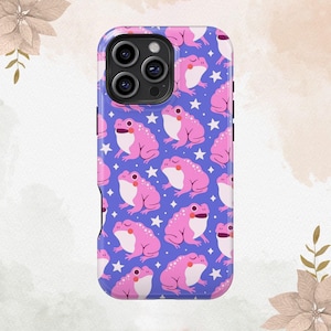 May include: A phone case with a repeating pattern of pink cartoon frogs and white stars on a blue background. The case has a glossy finish and a camera cutout.