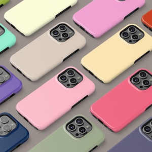 May include: Assortment of colourful phone cases with different camera cutouts. The cases are made of a smooth, matte material and are available in a variety of colours, including pink, yellow, blue, green, and red.