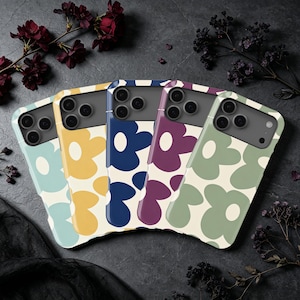 May include: Five smartphone cases arranged in a fan shape, each featuring a large, bold, repeating flower pattern. The cases come in light blue, yellow, dark blue, purple, and sage green, all with a cream-colored floral design and camera cutouts.
