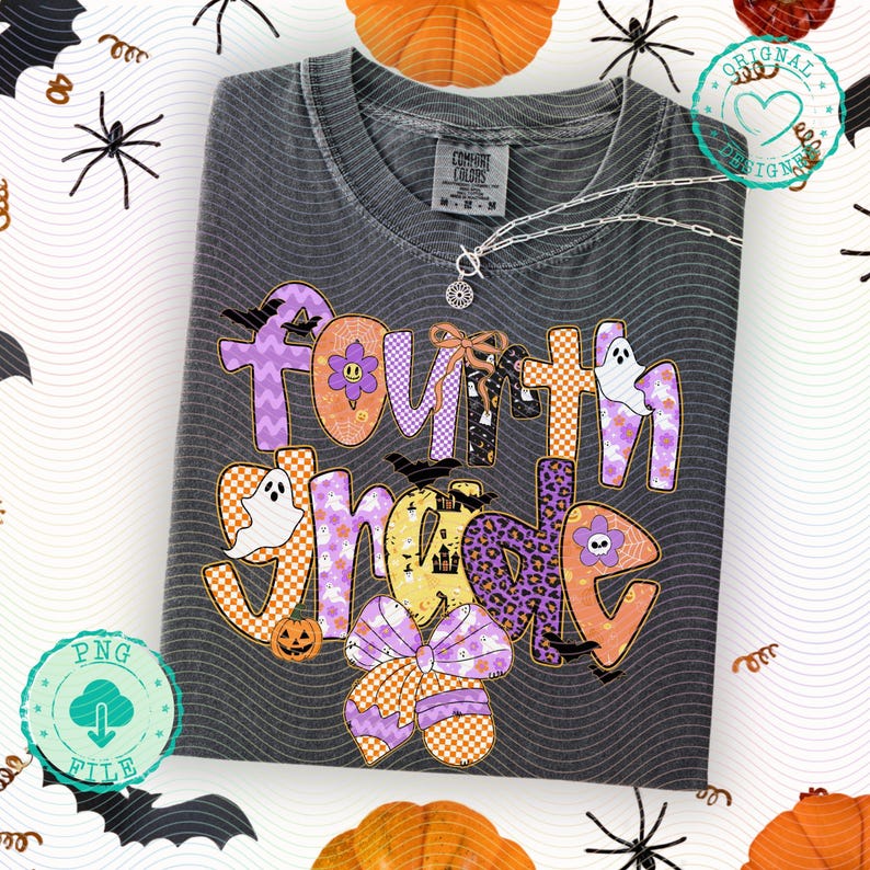 K&ouml;nnte beinhalten: Ein gefaltetes, anthrazitfarbenes T-Shirt mit dem Schriftzug "Fourth Grade" in einem farbenfrohen Halloween-Design. Das Design umfasst Geister, Flederm&auml;use, K&uuml;rbisse und Schleifen. Eine silberne Halskette mit Anh&auml;nger liegt &uuml;ber dem Shirt.
