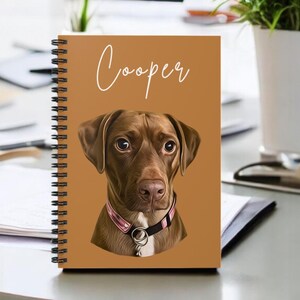 May include: A brown spiral notebook featuring a personalised illustration of a brown dog with the name "Cooper" printed in white on the front cover.