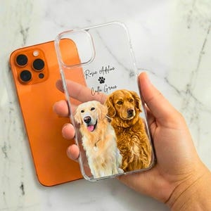 Könnte beinhalten: Transparente Handyhülle mit einem individuellen Porträt von zwei Golden Retrievern. Die Namen "Rosie Adeline" und "Calla Grace" sind aufgedruckt. Im Hintergrund ist ein orangefarbenes Telefon zu sehen.
