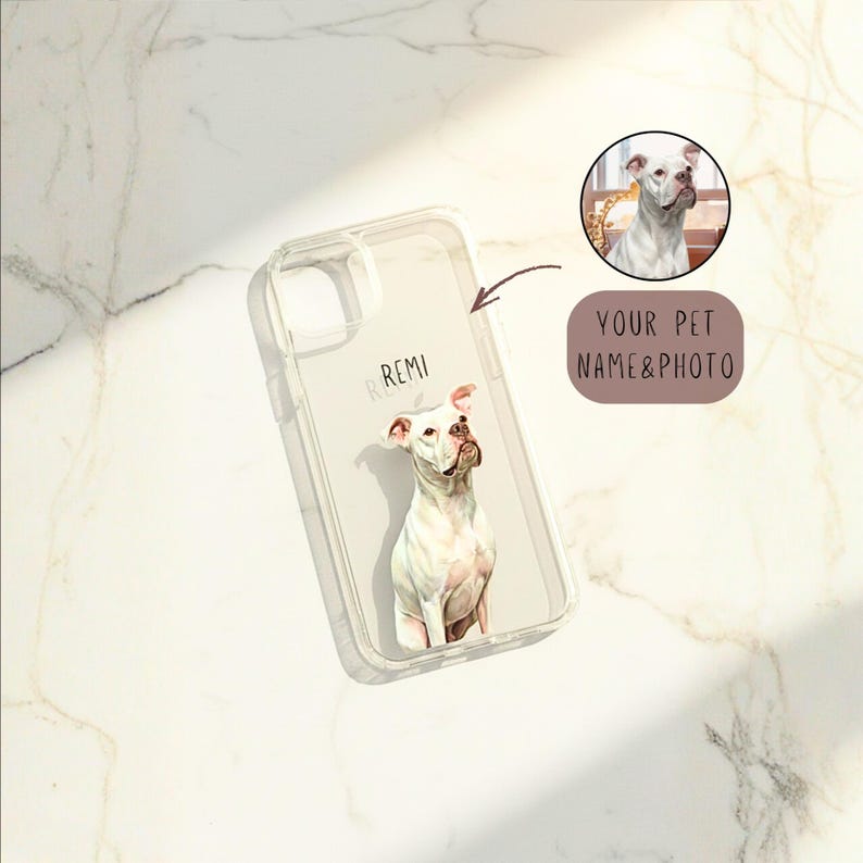 May include: Clear phone case featuring a watercolor portrait of a white dog with brown accents. The dog's name, "Remi," is printed in small, light letters. A small circular image of the dog is also included, along with the text "YOUR PET NAME & PHOTO."
