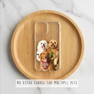 May include: Clear phone case featuring a custom design of three dogs. The dogs are a white dog with its tongue out, a brown dog with a green bow, and a golden retriever wearing a Christmas bandana. The case is on a wooden tray.