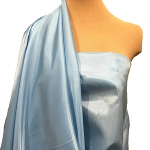 May include: A light blue satin fabric draped over a dress form. The fabric has a subtle sheen and is smooth to the touch.