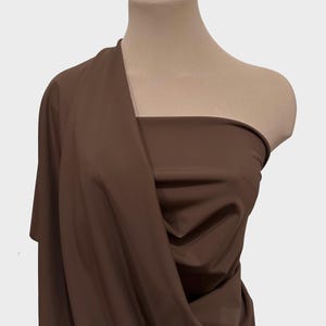 May include: A brown fabric draped over a mannequin's shoulders. The fabric is smooth and has a slight sheen.