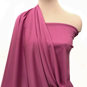 May include: A draped piece of mauve fabric on a white mannequin. The fabric is smooth and has a slight sheen.