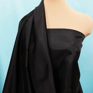 May include: Black fabric draped over a mannequin. The fabric is smooth and has a slight sheen.