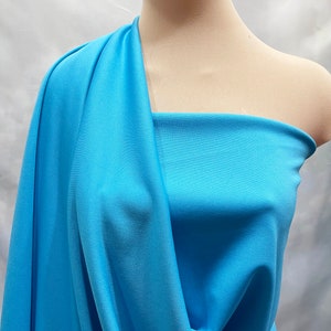 Puede incluir: Una muestra de tela azul claro drapeada sobre un maniquí. La tela tiene una superficie lisa y ligeramente texturizada.