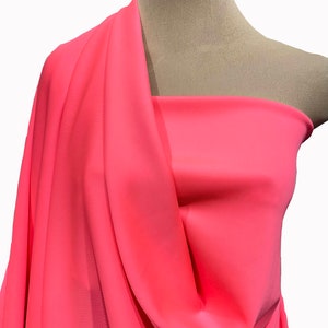 May include: A bright pink fabric swatch draped over a mannequin's shoulders. The fabric has a smooth, silky texture.