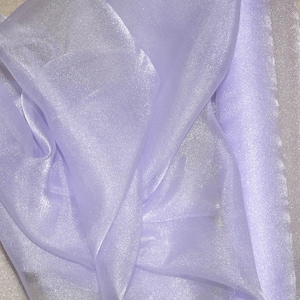 May include: A sheer, light purple fabric with a subtle shimmer. The fabric is soft and delicate, and it has a slightly iridescent sheen.