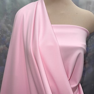 May include: A pale pink fabric swatch draped over a mannequin's shoulders. The fabric has a smooth, silky texture.