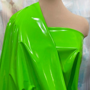 May include: A bright green, shiny, vinyl fabric. The fabric is draped over a dress form.