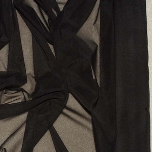 以下が含まれることがあります： 滑らかで絹のような質感の黒い透き通った生地。生地はドレープされ、折り畳まれ、その透明性を示しています。