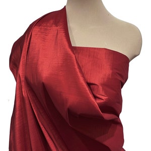 Könnte beinhalten: Ein tiefroter Taftstoff mit einem dezenten Glanz. Der Stoff ist über eine Schaufensterpuppe drapiert.