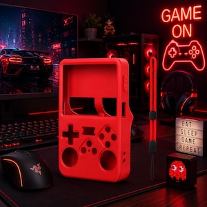 May include: A bright red silicone protective case for a handheld gaming console, featuring cutouts for buttons and a matching red wrist strap. The case has a rectangular frame with circular and cross-shaped openings for controls.