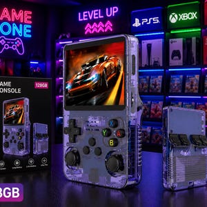 May include: A handheld game console with a transparent purple casing, featuring a color screen displaying a racing car, a directional pad, two analog sticks, and four colored action buttons labeled A, B, X, and Y, alongside its black retail box.