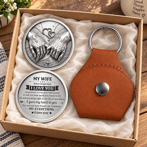 May include: A gift set containing two circular silver-toned metal tokens and a brown leather keychain with a metal ring. One token features embossed hands and the names Sophia and Henry. The other token displays the text My Wife Never forget that I LOVE YOU, including a sentimental message and heart symbols.