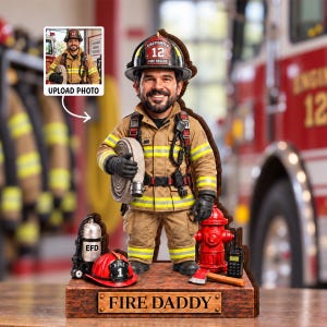 Puede incluir: Una figura personalizada de bombero con equipo de protección color canela, bandas reflectantes amarillas y un casco negro con el número 12. La base incluye una boca de incendio roja, un extintor plateado, un casco rojo con el número 1 y el texto FIRE DADDY.