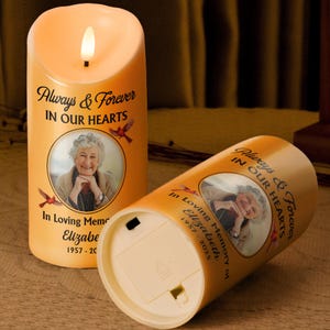 Puede incluir: Dos velas LED naranjas con efecto de llama parpadeante. Cada vela presenta una foto de una mujer, el texto "Always & Forever IN OUR HEARTS" y "In Loving Memory of Elizabeth 1957-2025".