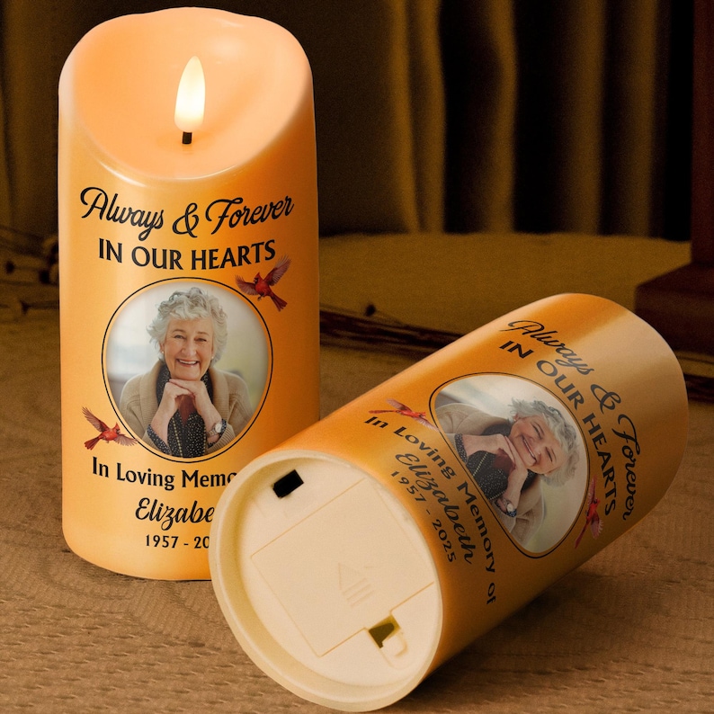 Puede incluir: Dos velas LED naranjas con efecto de llama parpadeante. Cada vela presenta una foto de una mujer, el texto "Always & Forever IN OUR HEARTS" y "In Loving Memory of Elizabeth 1957-2025".
