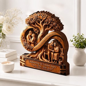 May include: A layered wooden sculpture featuring a carved tree with roses and two circular cutouts. One cutout shows a young couple with the name Lincoln, the other an older couple with the name Ruby. Text reads: Celebrating 50 Golden Years 1976-2026.