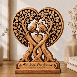 Peut inclure: Une sculpture en bois en forme de cœur représentant deux oiseaux perchés sur des branches, avec les prénoms Anna et David gravés sur les troncs. Un petit pendentif en forme de cœur affiche la date 06.06.2026 et la base porte l'inscription Two Souls, One Journey Forever & Always.