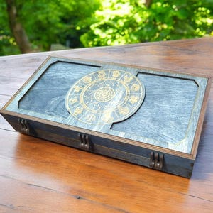 May include: A wooden box with a blue stained finish and a gold zodiac wheel design on the lid.