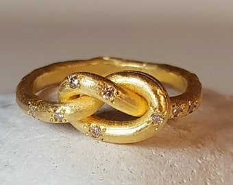 May include: A gold ring with a knot design and small diamonds set into the band.