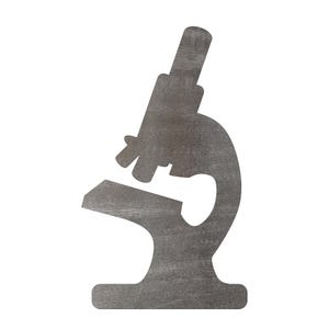 May include: A flat, two-dimensional silhouette of a microscope cut from a dark gray material. The object features the distinct shape of an optical instrument with an eyepiece, objective lenses, a stage, and a curved base, presented as a solid cutout.