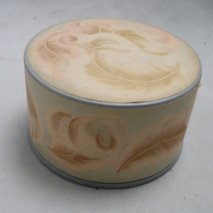 Peut inclure: Un poudrier rond vintage avec un design bleu clair et vert. Le poudrier est d&eacute;cor&eacute; d'un motif de plumes brunes et roses.