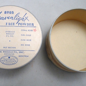 Peut inclure: Un compact de poudre pour le visage rond et blanc avec une &eacute;tiquette bleue et blanche qui indique "Avon Heavenlight Face Powder". L'&eacute;tiquette &eacute;num&egrave;re diff&eacute;rentes nuances de poudre pour le visage, notamment Rose Rachel, Naturel, Rachel, P&ecirc;che, Noix Brun, Corail Rose, Or Soleil, Rose Cr&eacute;puscule et Rose Rio. Le compact est ouvert et l'int&eacute;rieur est vide. L'&eacute;tiquette indique &eacute;galement "Poids moyen 2 1/2 oz." et "Avon Products, Inc. Distributeur New York Montr&eacute;al".