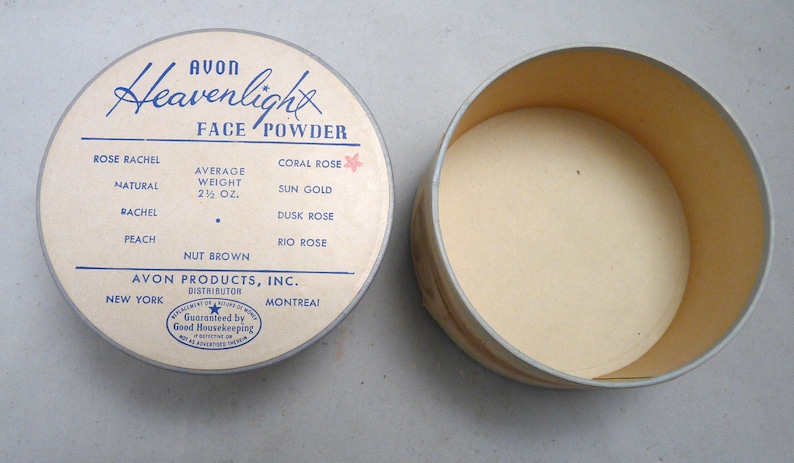 Peut inclure: Un compact de poudre pour le visage rond et blanc avec une &eacute;tiquette bleue et blanche qui indique "Avon Heavenlight Face Powder". L'&eacute;tiquette &eacute;num&egrave;re diff&eacute;rentes nuances de poudre pour le visage, notamment Rose Rachel, Naturel, Rachel, P&ecirc;che, Noix Brun, Corail Rose, Or Soleil, Rose Cr&eacute;puscule et Rose Rio. Le compact est ouvert et l'int&eacute;rieur est vide. L'&eacute;tiquette indique &eacute;galement "Poids moyen 2 1/2 oz." et "Avon Products, Inc. Distributeur New York Montr&eacute;al".
